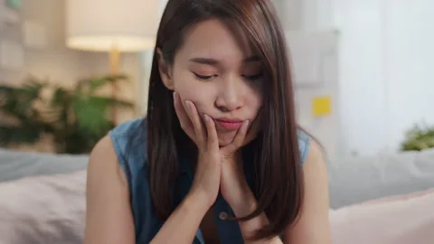 Thoughtful Girl thinking to solve a problem sits on sofa alone in living room Video stock 132813651