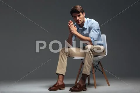 Thoughtful handsome young man sitting on chair and looking camera Stock Photos