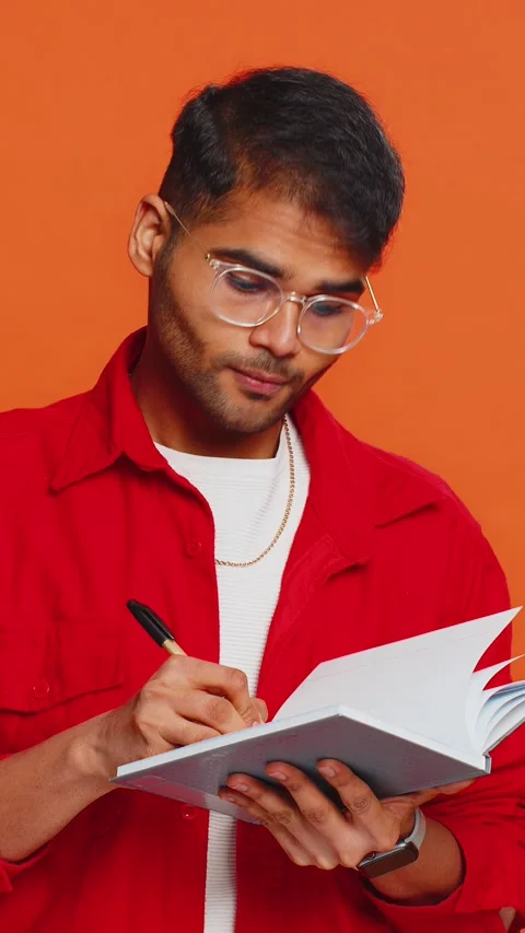 Thoughtful Indian man making notes, writing down thoughts with pen into notepad Stock Footage 348055127