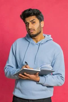 Thoughtful Indian man making notes, writing down thoughts with pen into notepad Stock Photos