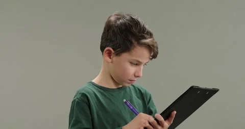 Thoughtful little boy making notes, writing down ideas, thoughts with pen into Stock Footage 260765243