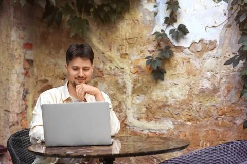 Thoughtful male programmer working with laptop at table in street cafe Stock-Fotos