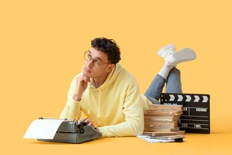 Thoughtful male screenwriter using typewriter on yellow background Stock Photos
