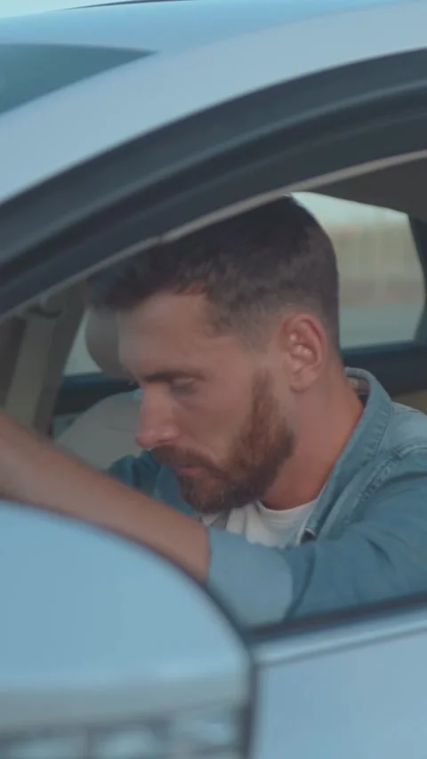 A Thoughtful Man Behind the Wheel Driving a Stylish Car Through the City Streets Stock Footage 303780135