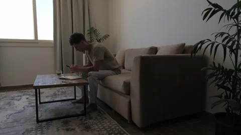 Thoughtful man checking smartphone and considering everyday expenses at home Stockbeeldmateriaal 346249072