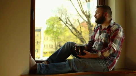 Thoughtful man drink coffee, sitting on windowsill Stock Footage 62824435