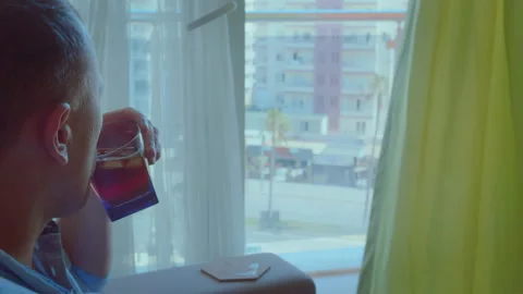 Thoughtful Man Drinking Cold Beverage by Window, Side View, Camera Tracking Stock Footage 310674786