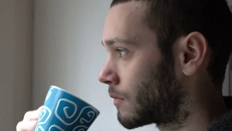 Thoughtful Man Drinks Cup of Coffee near a Window Stock Footage 72099756