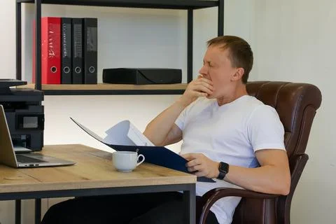 Thoughtful man examining documents in office setting Stock Photos