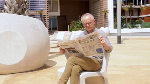 Thoughtful Man with Glasses Reading a Printed Newspaper Stock Footage 311894732