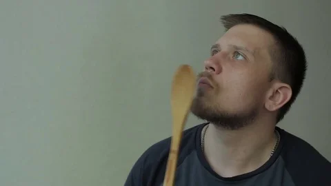 Thoughtful man knocking on his lips with wooden spoon. Video stock 77413460