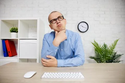Thoughtful man looking away while sitting at his working place in office Stock Photos