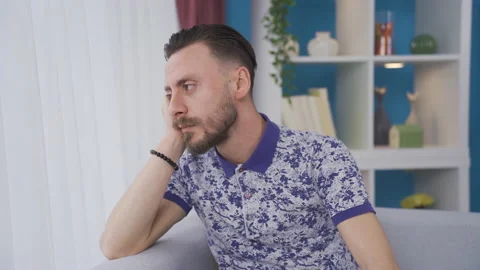 Thoughtful man looking out the window at home. Video stock 230938635