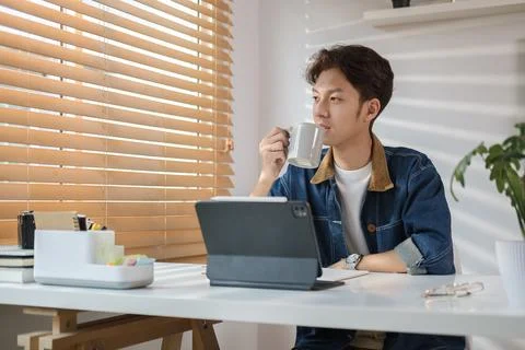 Thoughtful man looking through window and drinking morning coffee in home o.. Stock Photos