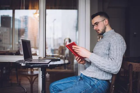 Thoughtful man reading book at table Stock Photos