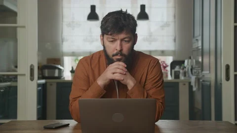 Thoughtful man reading a message on his laptop Stockbeeldmateriaal 195808166