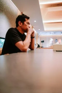 Thoughtful Man Sitting Alone at Cafe Table Stock Photos