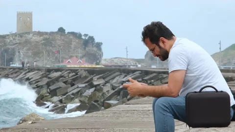 Thoughtful man sitting on the coast Stock Footage 224549714