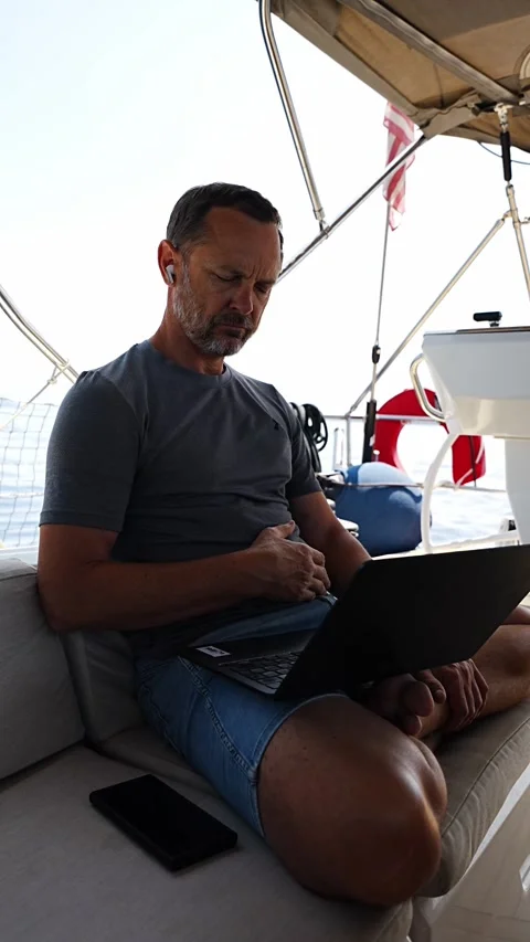 Thoughtful man sitting with laptop on a sailing yacht during a work break Stock Footage 345659006