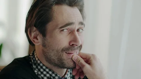 Thoughtful man smiling to himself unaware of being watched and then looking to Stock Footage 88598013