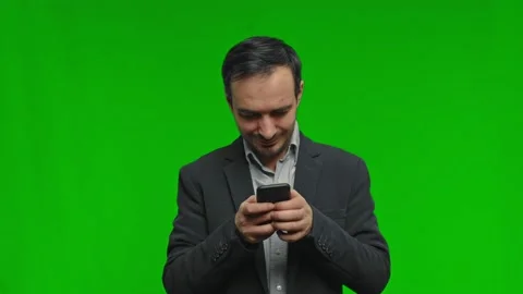 Thoughtful man in suit using phone over isolated green background Stock Footage 171799535