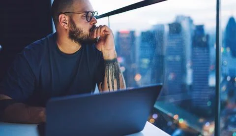 Thoughtful man touching lips working in evening Foto stock