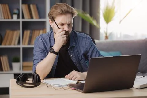 Thoughtful man using laptop during remote work Stock-Fotos