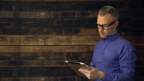 Thoughtful man using tablet device turns and smiles Stock Footage 85423660