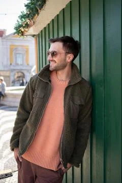Thoughtful man in warm jacket looking away while leaning on house Stock-Fotos