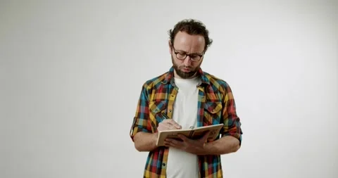 Thoughtful Man Writing in Notebook on White Background Stock Footage 344272060