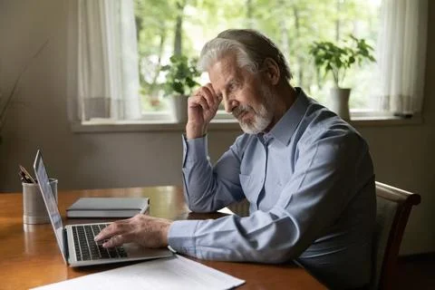Thoughtful mature man study pc on retirement read electronic guide 写真素材