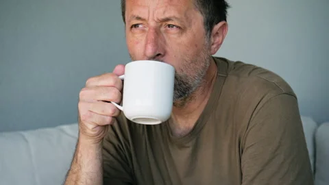 Thoughtful middle aged man with beard holding a white coffee mug looking pe.. Stock Footage 346809346