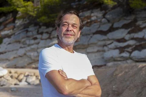 Thoughtful middle aged man standing by sunlit stone wall in Croa Stock-Fotos