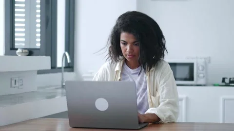 Thoughtful multitasking young woman using laptop computer for remote work or Stock Footage 212419762