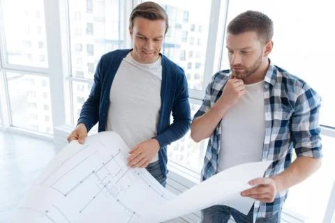 Thoughtful nice men looking at the engineering drawing Stock Photos