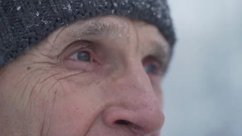 Thoughtful old man in grey hat looks at white snowflakes Video stock 157831050