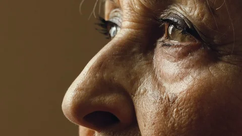 Thoughtful old woman's eyes looking away: side portrait of elderly woman eyes Stock Footage