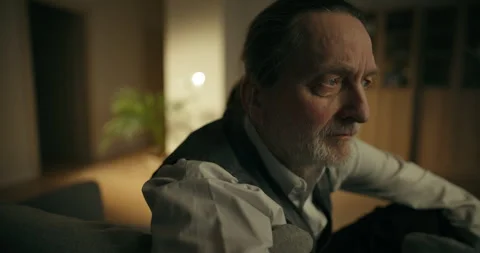 Thoughtful older bearded man sitting indoors in warm soft light Stock Footage 336277231