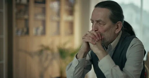 Thoughtful older bearded man sitting at a table in a quiet office Stock Footage 336277706
