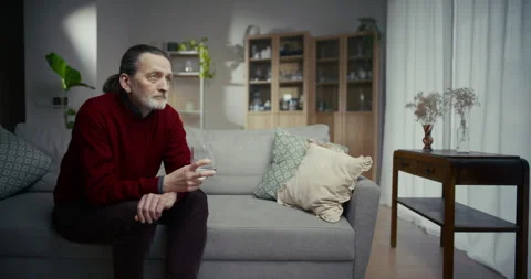 Thoughtful older man resting on sofa in a bright modern living room Видео 336289014