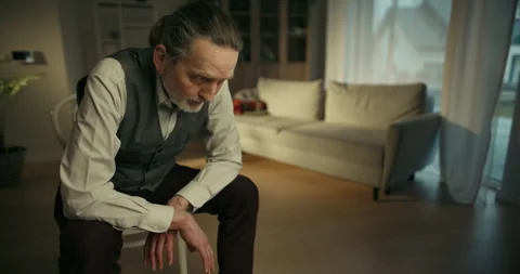 Thoughtful older man sitting in a modern living room Stock Footage 336288316