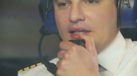 Thoughtful pilot talking to dispatcher over radio set and navigating plane Stock Footage 64601143