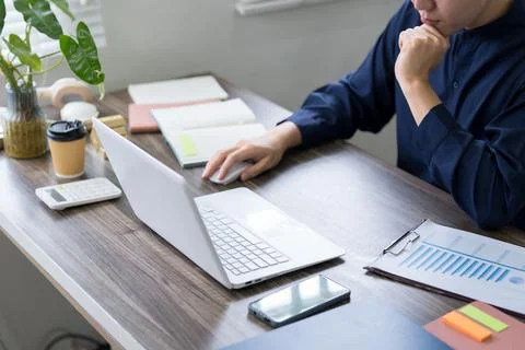 Thoughtful professional analyzing business data on laptop while reviewing f.. 스톡 사진
