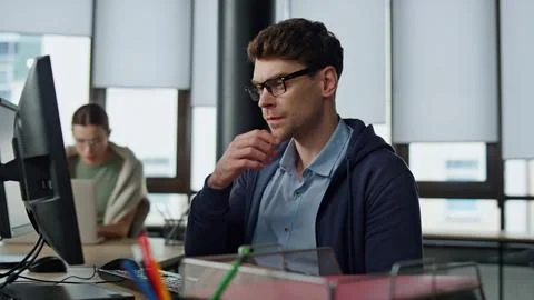 Thoughtful programmer looking computer at desk. Focused it man analysing code Stock Photos