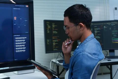 Thoughtful Programmer Reviewing Code on a Digital Tablet Stock Photos