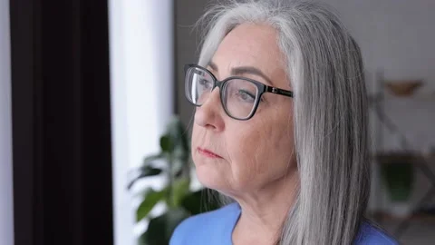 Thoughtful sad elderly gray-haired woman looking away thinking about retirement Stock Footage 181507970