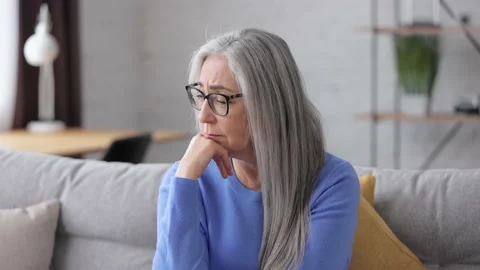 Thoughtful sad elderly gray-haired woman looking away thinking about retirement Stock Footage 213278862