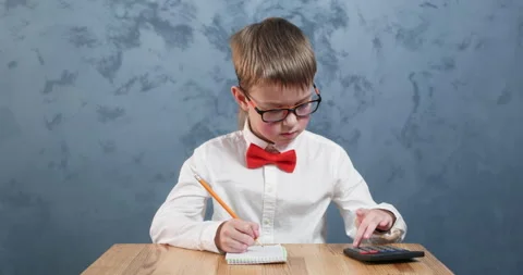Thoughtful schoolboy in glasses writes down math calculations Stock Footage 304363049