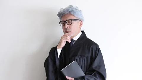 Thoughtful Senior Judge Holding Document and Thinking in Courtroom Stock Footage 343957452
