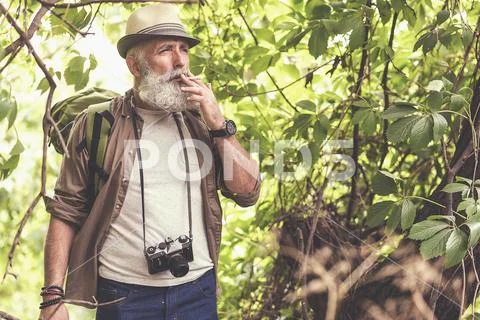 Thoughtful senior male tourist inhaling nicotine in wood Stock Photos